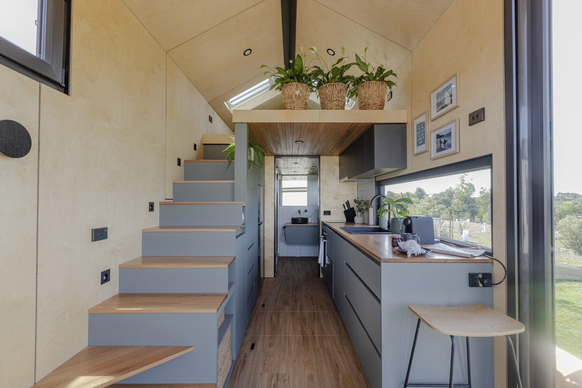 Tiny home on wheels interior with kitchen, stairs and natural timber finishes