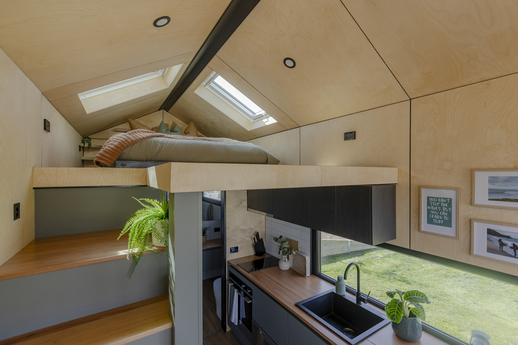 Tiny home on wheels interior – plywood ceiling and skylight Interior layout of a Manuka tiny home on wheels showing a compact kitchen, plywood lining and overhead skylight.