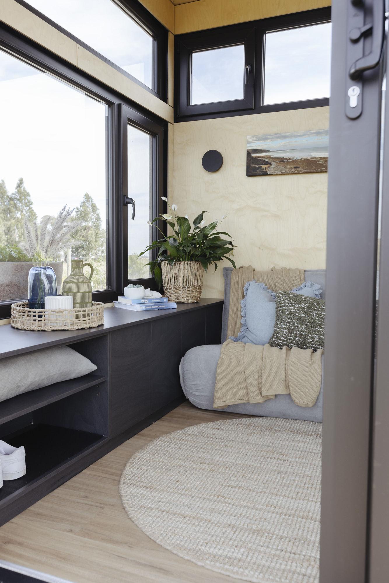 Tiny Home Lounge with Custom Bench, Daybed & Coastal Views Tiny house living area with built-in bench seat and panoramic windows