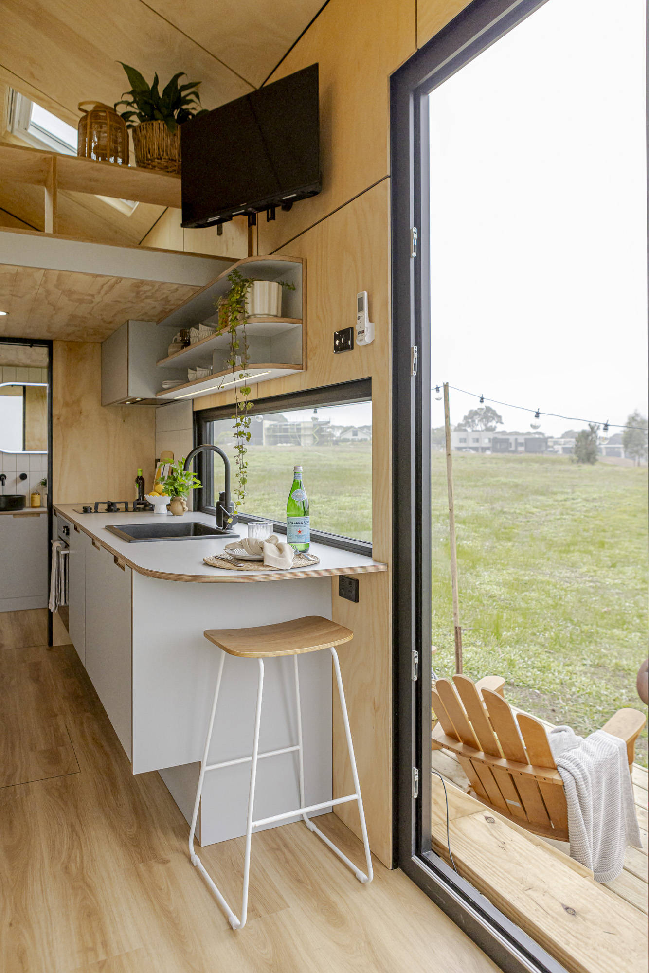 Interior of a Manuka Tiny Home on Wheels with timber finishes, kitchen and large window