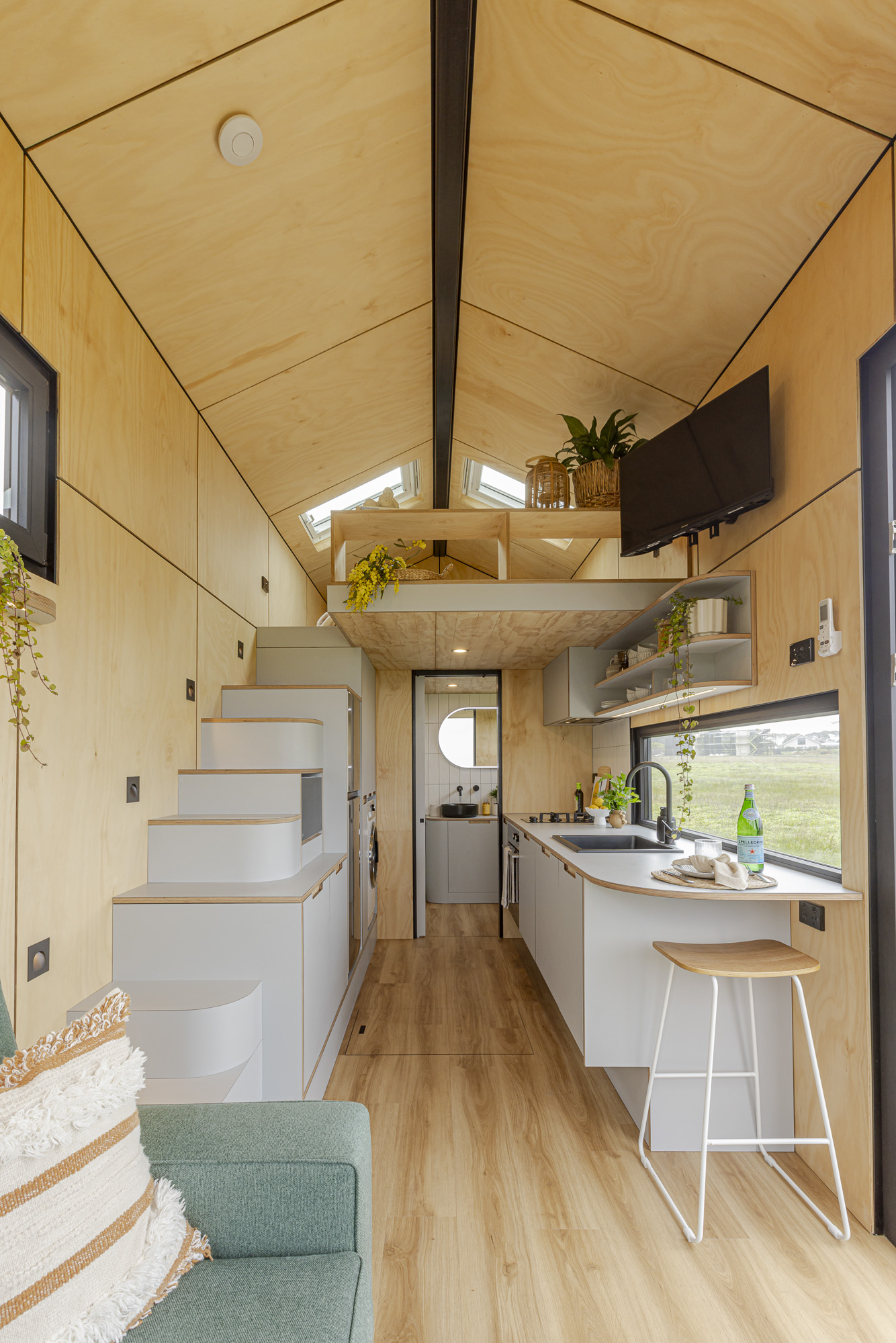 Luxe Loft tiny home interior showing the kitchen, staircase and warm timber finishes