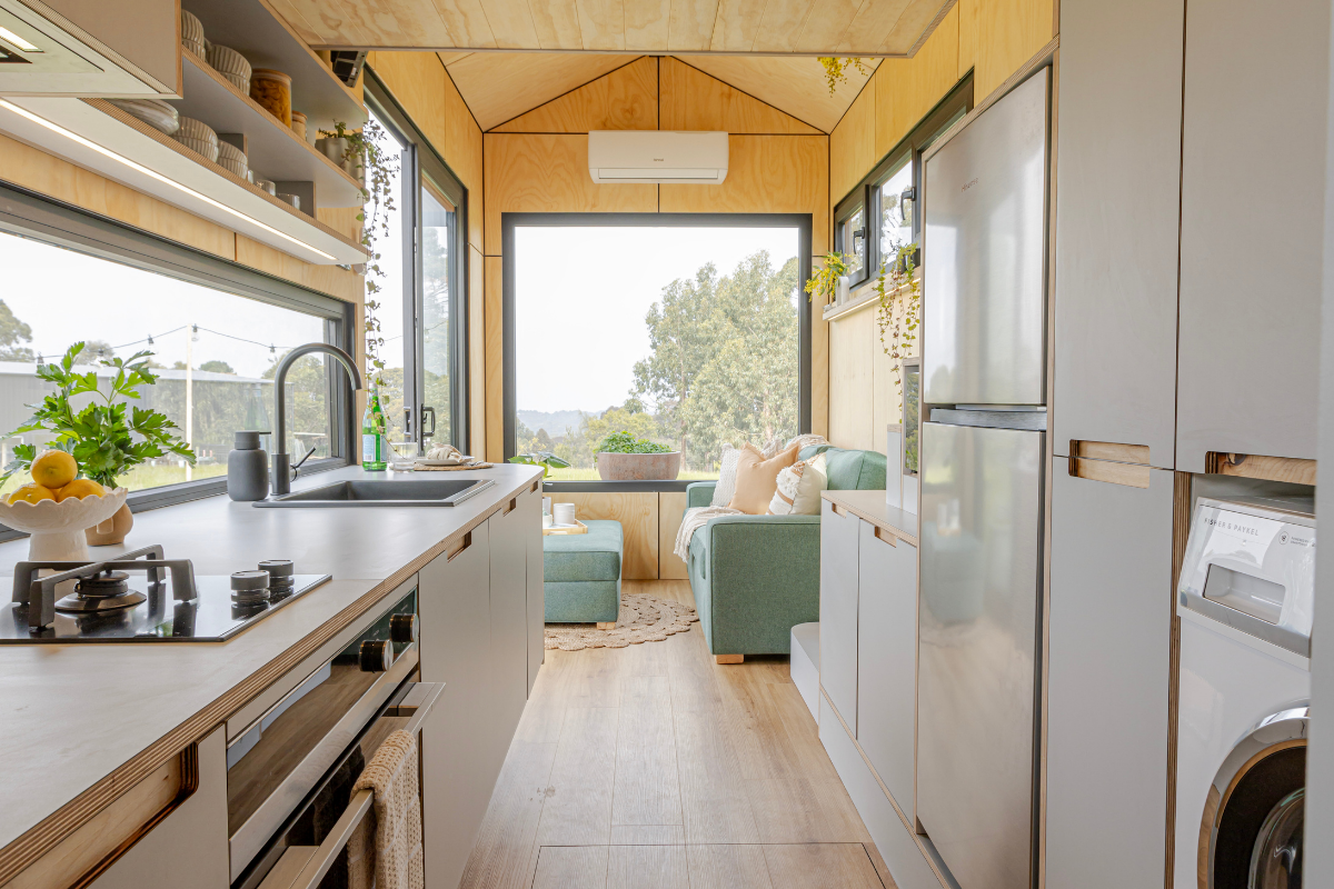 Interior of the Luxe Loft 7.2m tiny home on wheels with kitchen, dining bench and loft bedroom