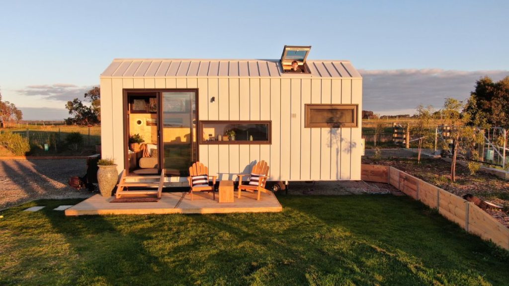 Tiny home on wheels with deck in a rural setting
