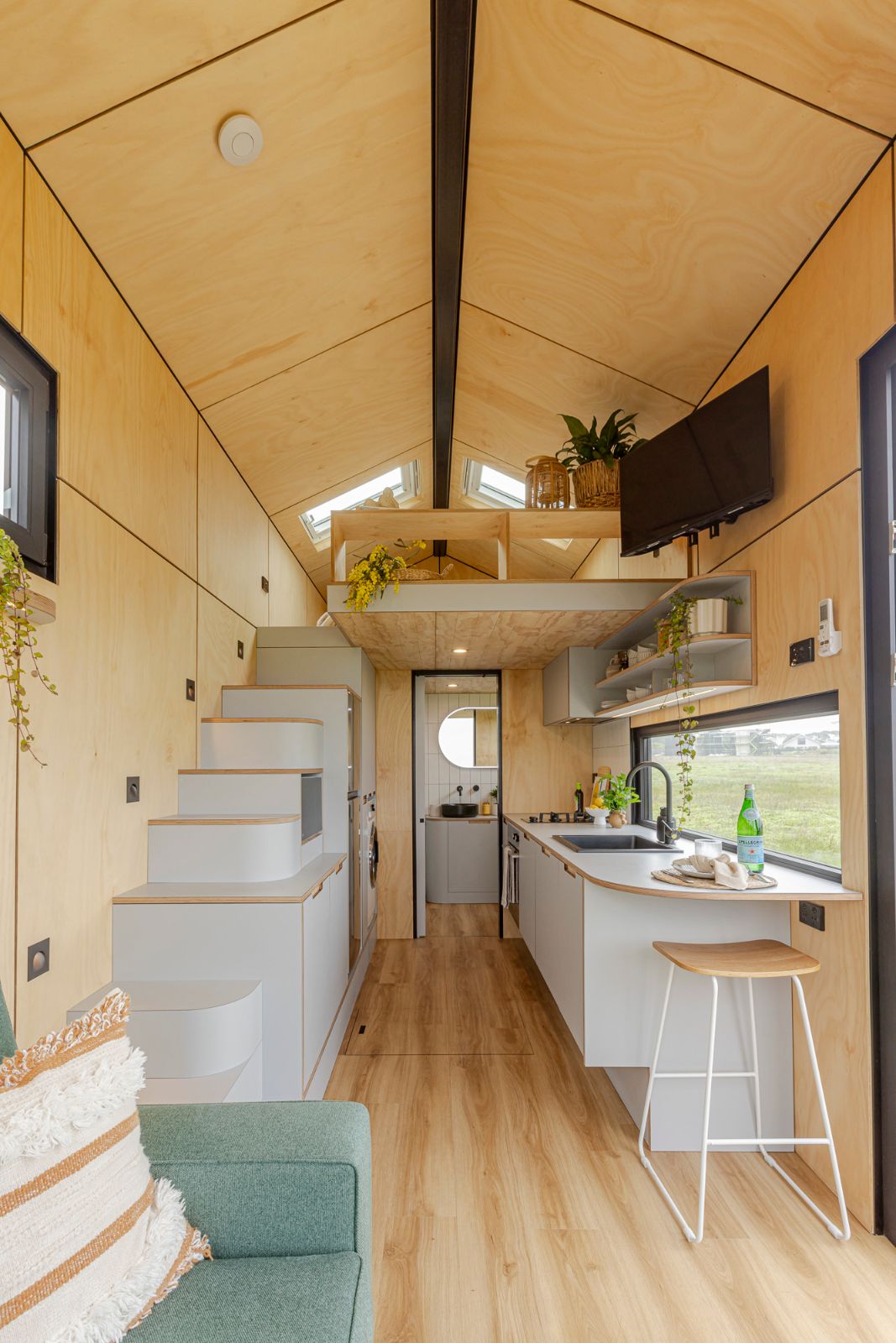 Luxe Loft tiny home interior showing the kitchen, staircase and warm timber finishes